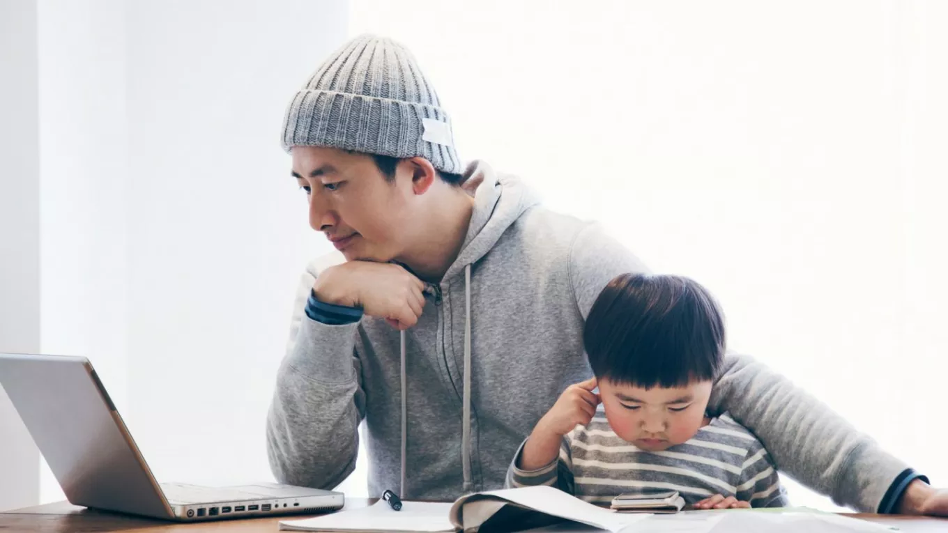 hombre con hijo trabajando en computador portatil 